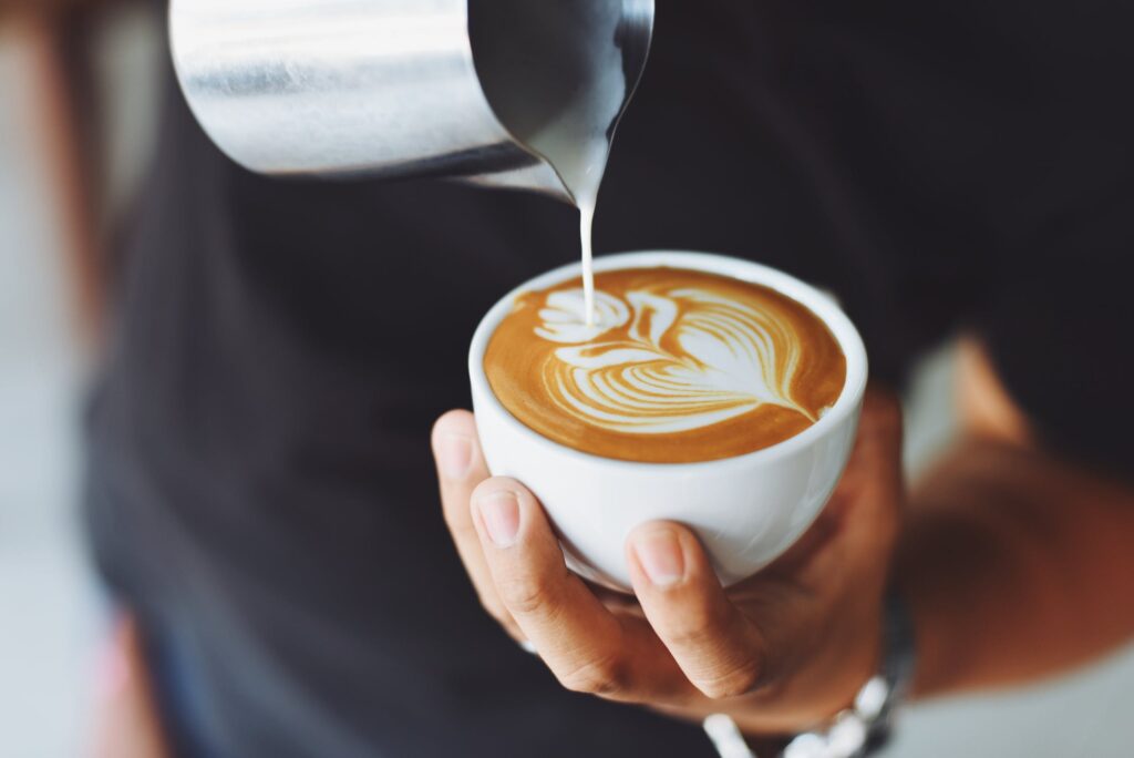 Barista Doing Latte Art On A Coffee In A White Mug.