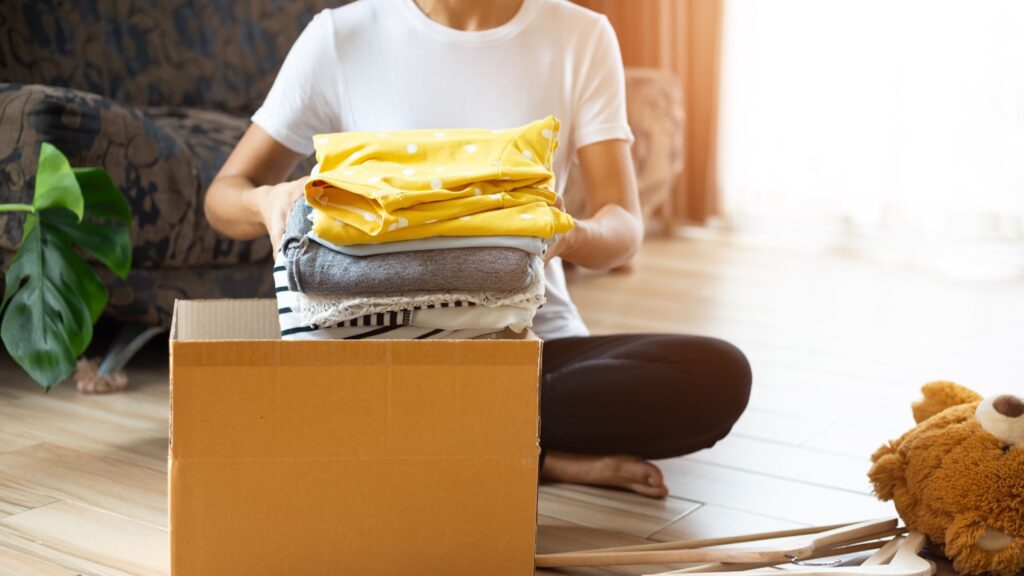 Woman Putting Old Clothes In A Box To Donate.